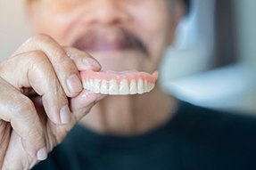 Patient in Dallas holding their dentures