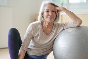 Senior woman smiling while resting against balance ball