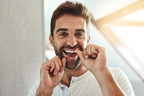 Man smiling while flossing his teeth