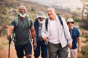 man smiling with dentures and hiking with friends