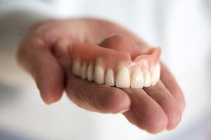 Hand holding an upper denture