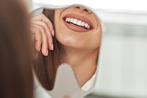 Woman’s perfect teeth reflected in tooth-shaped mirror
