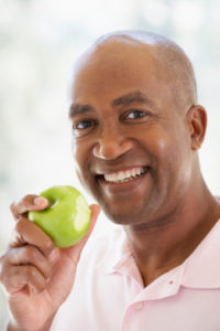 Middle Aged Man Eating Green Apple And Smiling At The Camera