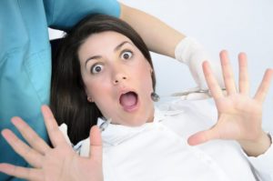 woman in dental chair expressing fear