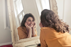 Woman looking at smile in mirror after dental fluorosis treatment in North Dallas.