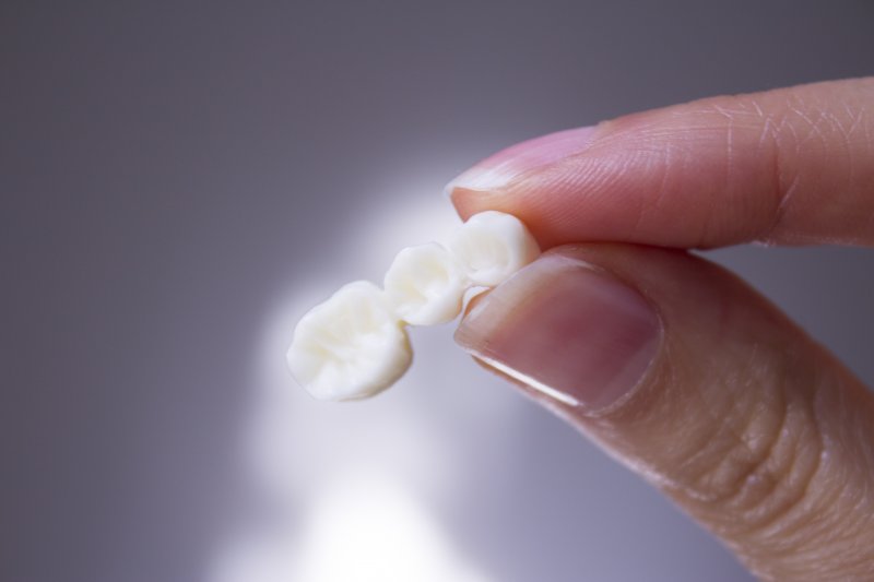 person holding dental bridge in hands