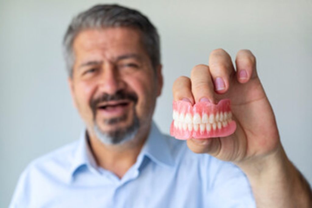 Man holding his white dentures.