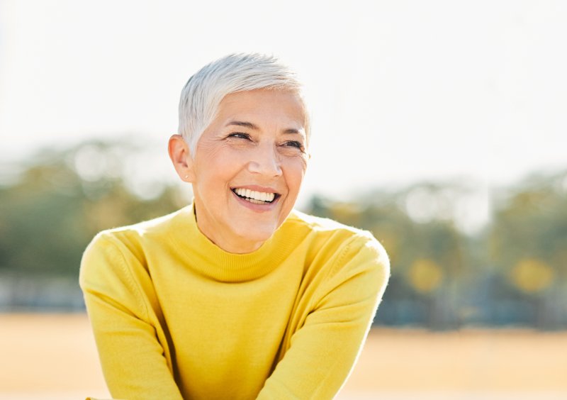a woman smiling and wearing a bright yellow shirt