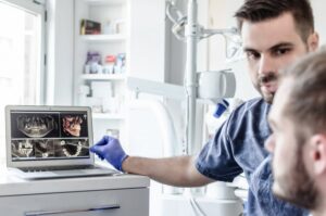 a dentist showing a patient their diagnostic images on a computer screen